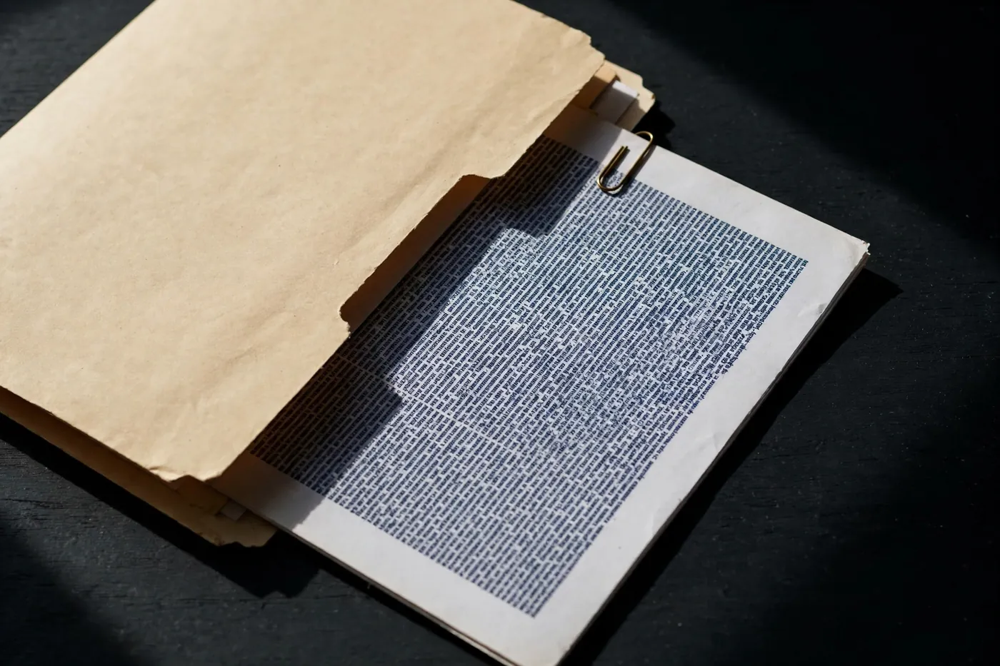A manila folder with a page of dense text half drawn out